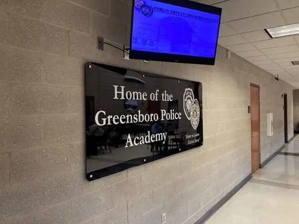 Interior view of the Greensboro Police Academy, featuring a wall sign and a monitor displaying information.