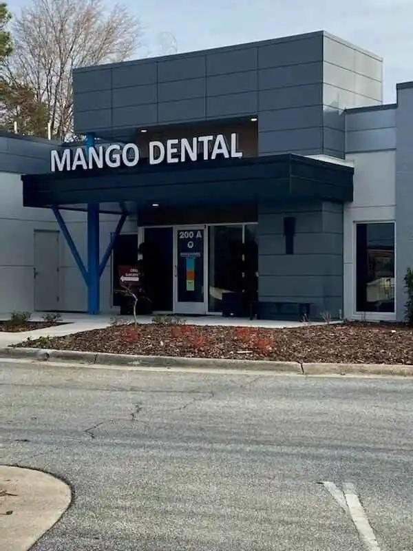 Exterior view of a modern dental office named "Mango Dental," featuring a channel letter sleek design and signage, set against a clear sky.